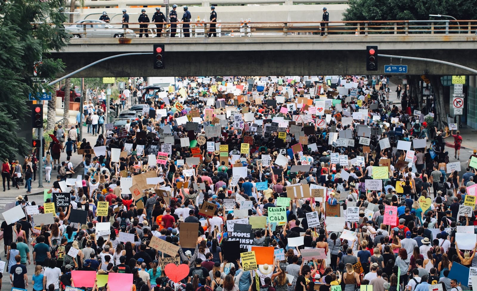 A large crowd filling a street, holding up handmade protest signs.